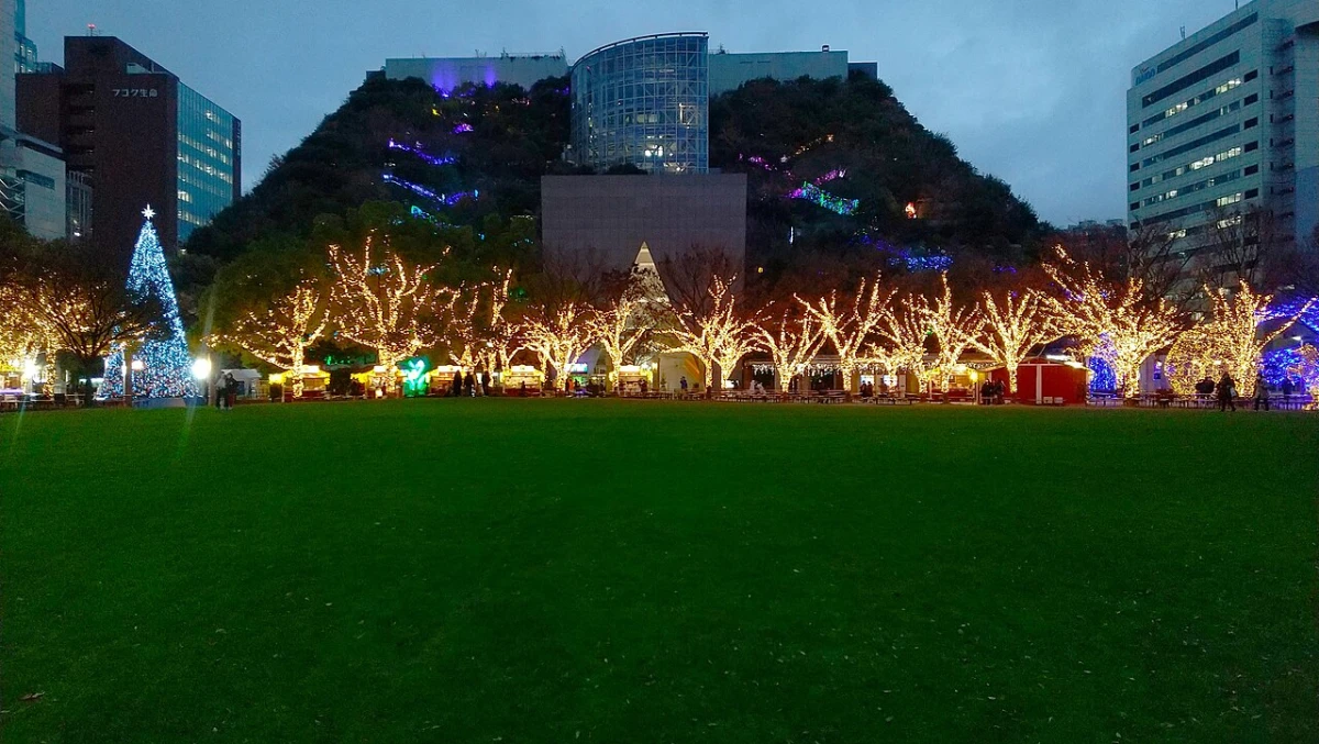 Tenjin Central Park in Fukuoka at dusk, with lit trees in front of the stepped green roof of ACROS Fukuoka